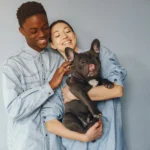 casal alegre segurando um cachorro ilustrando o assunto de cuidados com a saúde do seu animal de estimação