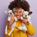 moça segurando dois cachorros filhotes ilustrando o assunto de cuidados com animais de estimacao